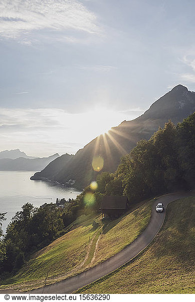 Switzerland  Gersau  Schwyz  Car driving along winding road at sunset with LakeÂ LucerneÂ in background