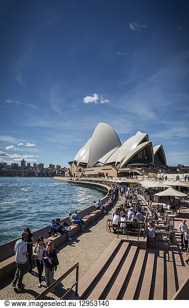 Sydney opera house and harbour promenade outdoor cafes in australia on sunny day.