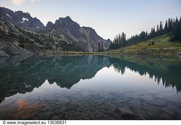 Symmetry view of lake by mountains against cloudy sky at Olympic National Park