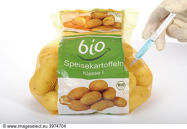 Syringe into potatoes with organic labeling on the label  symbolic picture  fraud with food with the BIO label