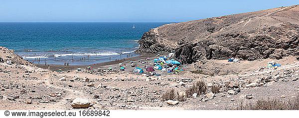Szenerie eines felsigen Strandes voller Menschen auf der Insel Gran Canaria