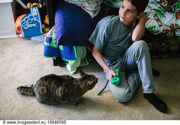 Tabby cat sits next to boy as he holds his video game controller