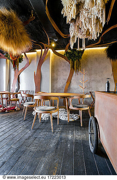 Tables and chairs arranged on wooden floor at modern restaurant
