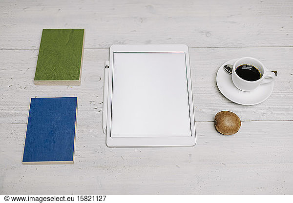 Tablet  cup of coffee  kiwi and samples on wooden surface