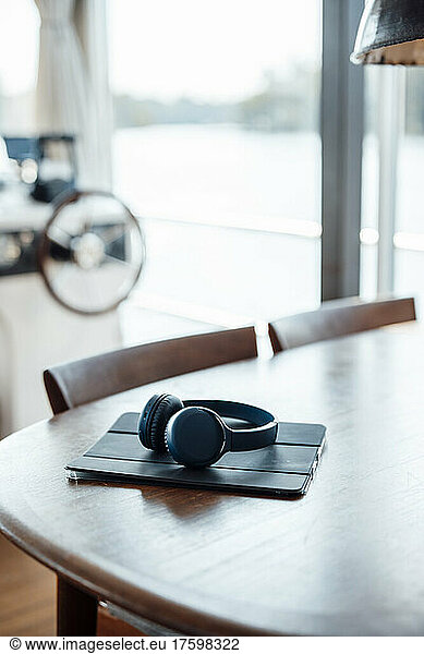 Tablet PC and wireless headphones on wooden table at houseboat