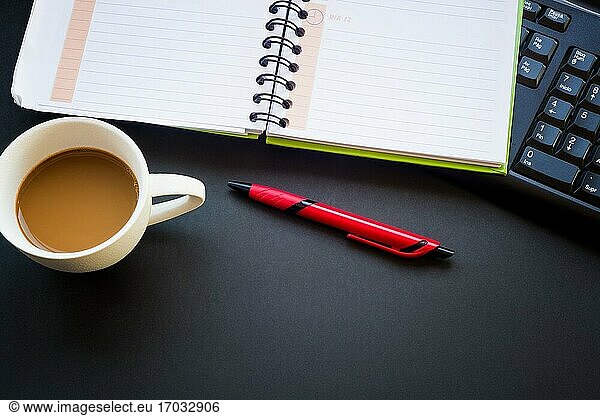 Tagebuch mit Kaffeetasse und Stift.