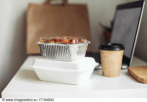 Take away coffee cup  delivery boxes  craft bag and a laptop at home