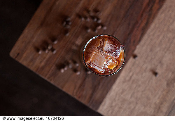 Tall Glass of cold brew iced coffee on a wooden coffee table