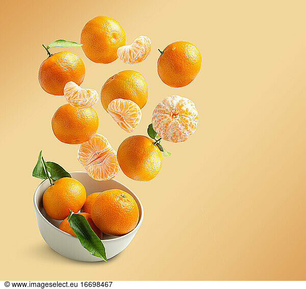 Tangerines flying isolated from orange background with copy spac