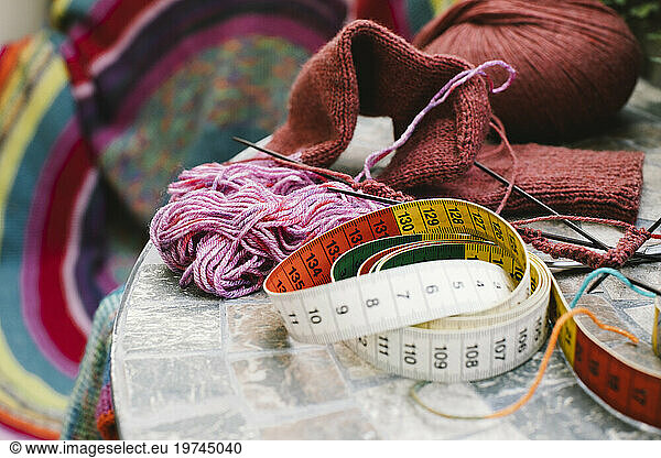 Tape measure with wool and knitting needles on table