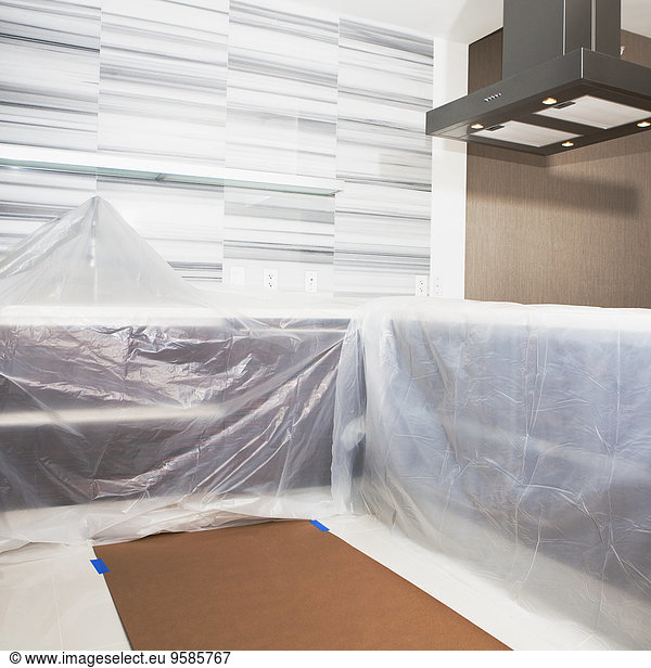 Tarps covering surfaces in modern kitchen under renovation