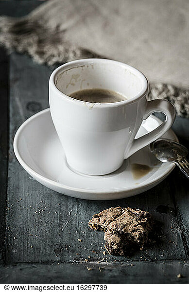 Tasse Kaffee und Reste von Schokoladenkeksen auf grauem Holz