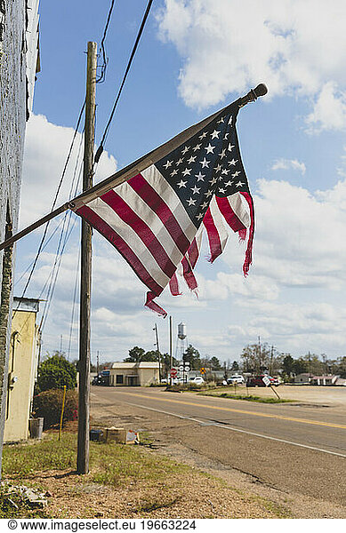 Tattered American flag flying on a building on Main Street.
