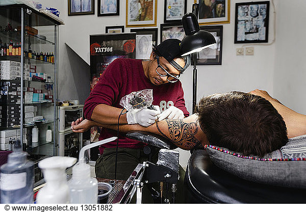 Tattoo artist tattooing customer's shoulder
