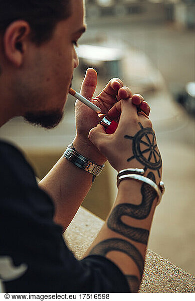 Tattooed boy lighting a cigar with a lighter