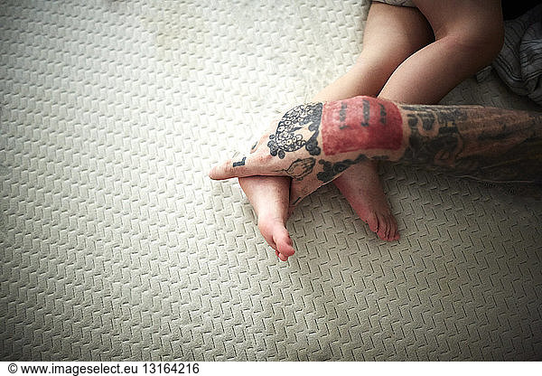 Tattooed hand resting on boy's legs