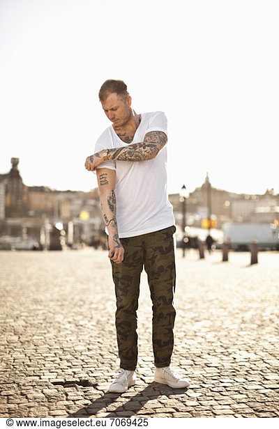 Tattooed man in casual wear standing on street