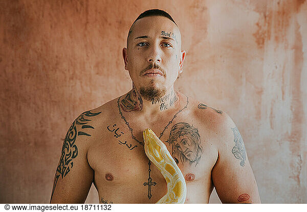 tattooed man looking at camera with a snake on his chest