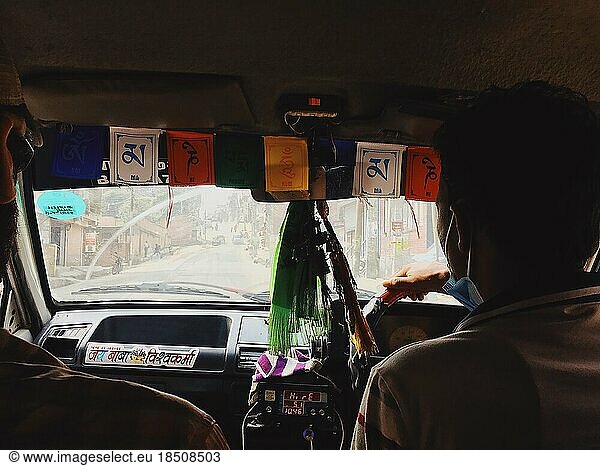 Taxi driver driving through dusty city with flags in window