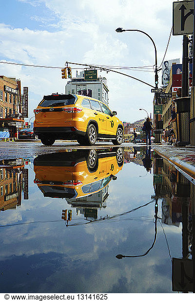 Taxi on wet road reflecting in puddle