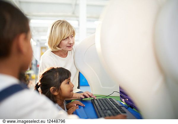 Teacher and schoolgirl using computer in science center