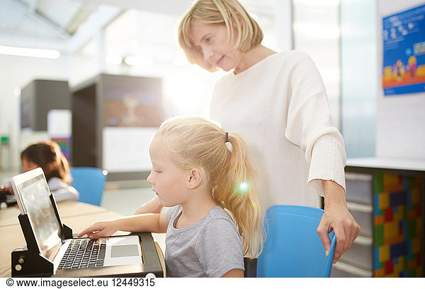 Teacher and schoolgirl using laptop in science center