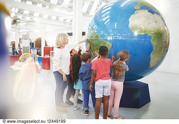 Teacher and students touching large globe in science center