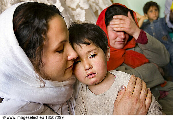 Teacher comforts a crying child at a Kabul day care  while another teacher looks on in sadness.