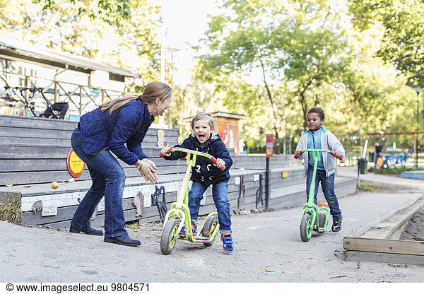 Teacher motivating children on push scooters during race