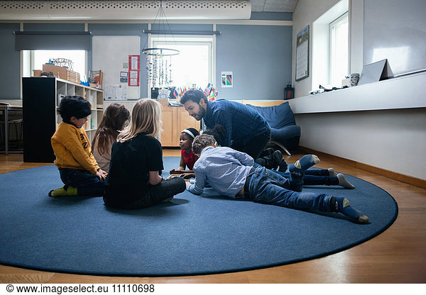 Teacher playing with children on floor at school