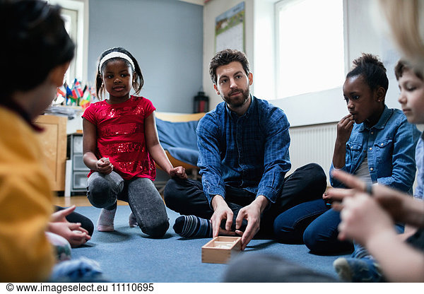 Teacher playing with children while sitting in classroom