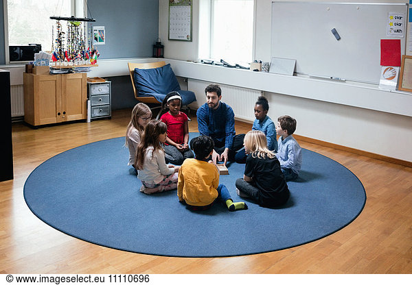 Teacher playing with students while sitting on floor at school