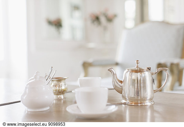 Teacups and silver teapot on table
