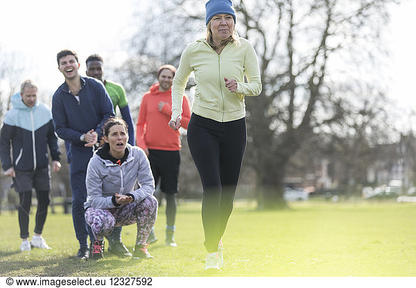 Team cheering woman running in park