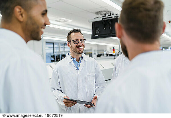 Team of competent electrical technicians in lab coats having meeting in electronics factory