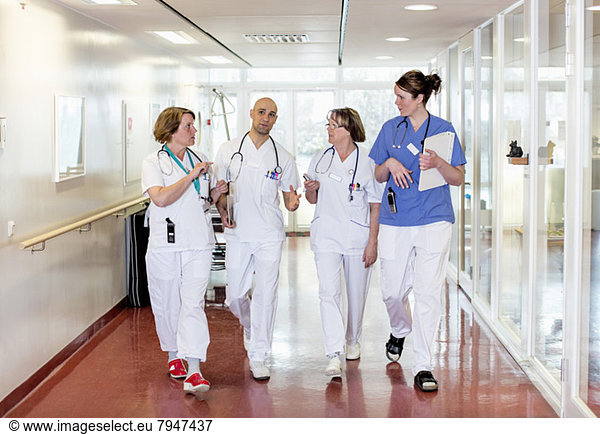 Team of doctors communicating while walking in hospital corridor