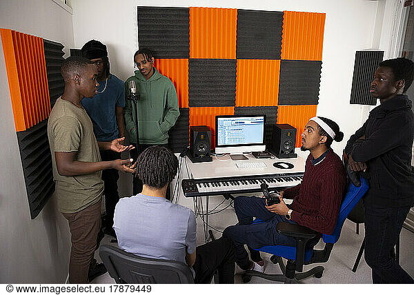 Team of music artists discussing while sitting in recording studio