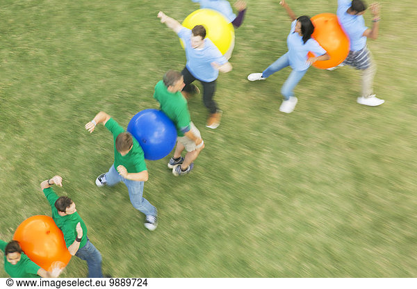 Teammates performing fitness ball team building activity