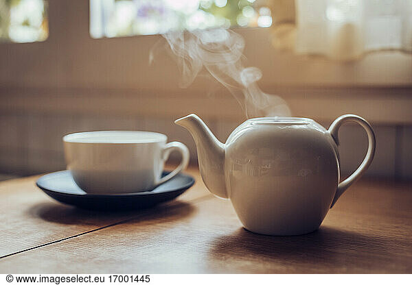 Teapot giving off smoke on top of kitchen table