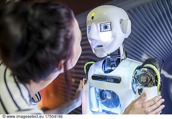 Tech developer looking at human robot in workshop