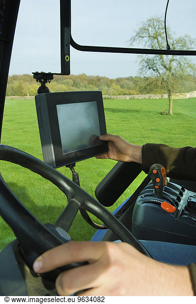 Technical equipment aboard a tractor  a hand touching a touch screen.