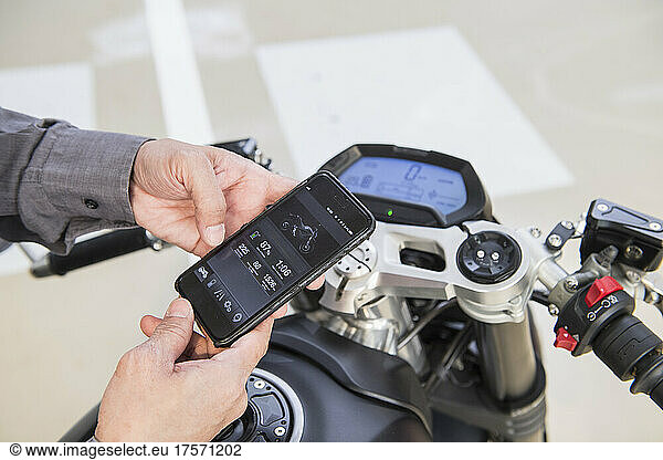 technician checking electric motorcycle with smartphone at workshop