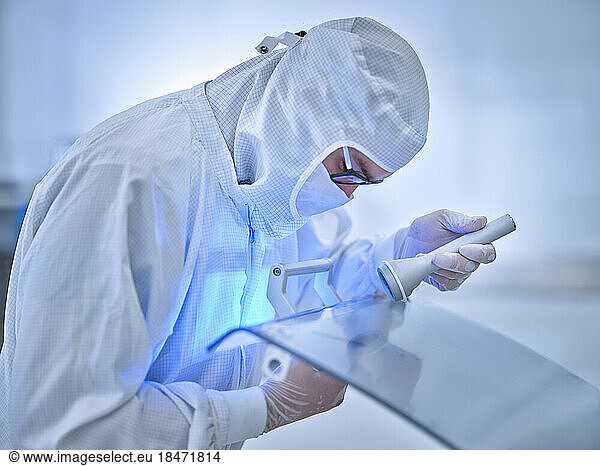 Technician examining surface for dirt with blue light in laboratory