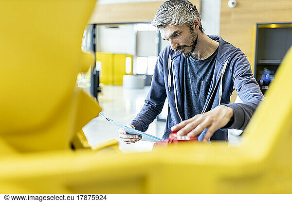 Technician inspecting industrial robot in factory