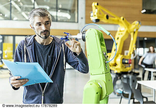 Technician inspecting industrial robot in factory