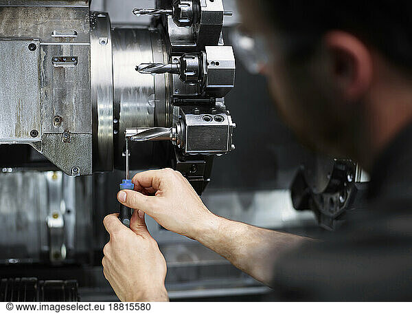 Technician repairing drill bit on metal machine in factory