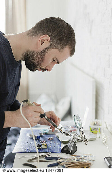 Technician repairing equipment using soldering iron at workshop