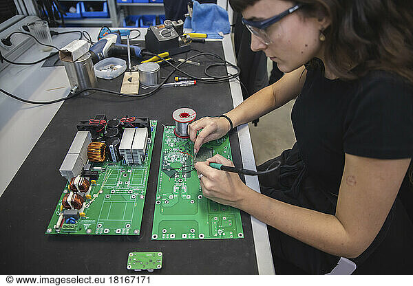 Technician soldering motherboard in electronics industry