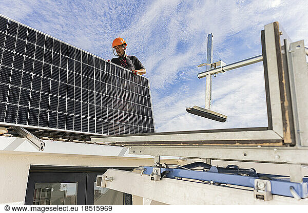 Technician standing with solar panel under sky