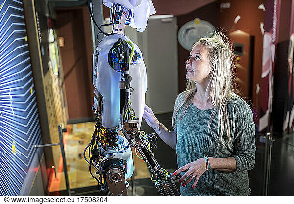 Technician talking and looking at human robot in workshop